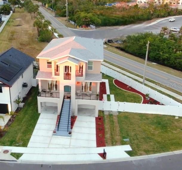 An elevated house with a front staircase sits on a corner lot near a road — 5324 JOBETH DRIVE, NEW PORT RICHEY, FL