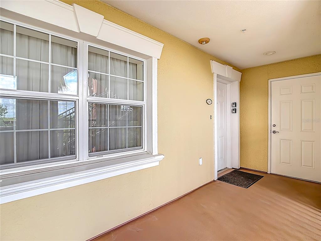 A covered outdoor entryway features a large window, a white door, and a side door — 1116 SUNSET VIEW CIRCLE UNIT 304, REUNION, FL