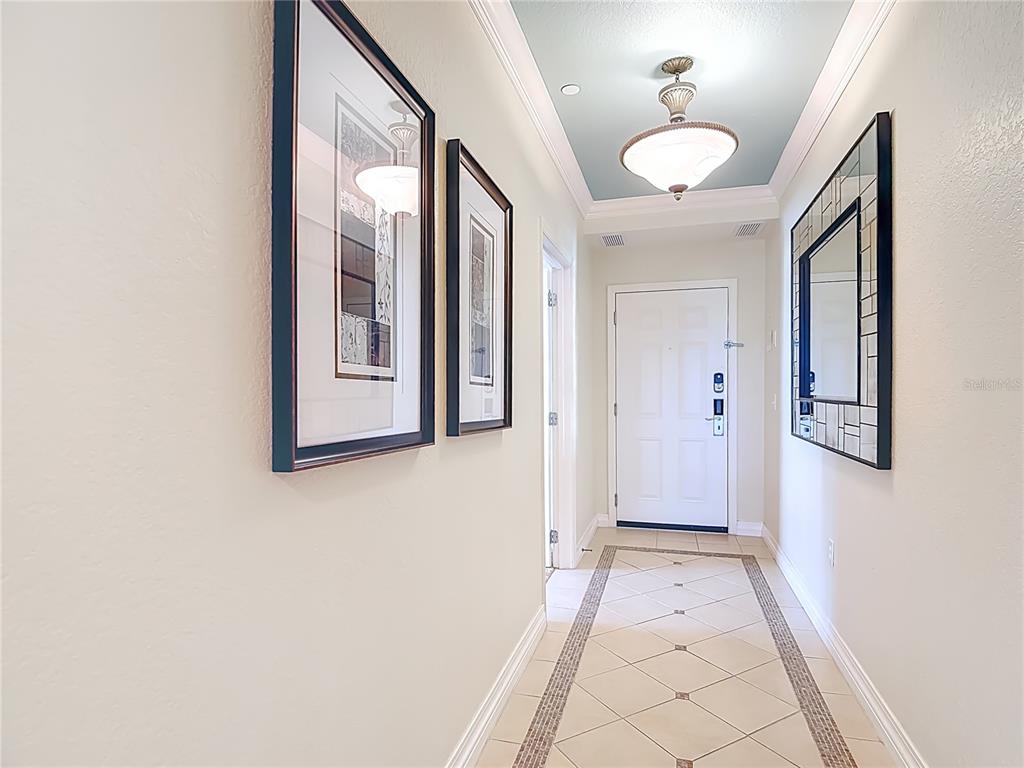 A bright entryway features a tiled floor, a blue tray ceiling, and wall-mounted artwork — 1116 SUNSET VIEW CIRCLE UNIT 304, REUNION, FL