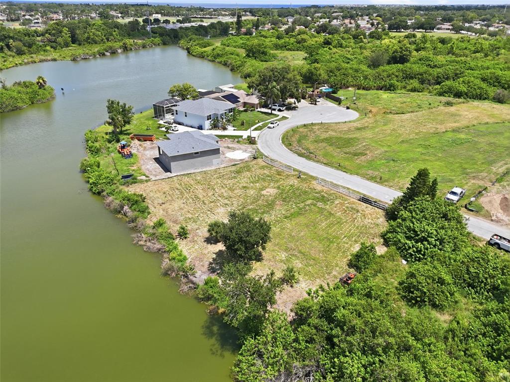 An aerial view shows a waterfront property with two houses and a large grassy lot — 1504 JACKSON DRIVE, HOLIDAY, FL
