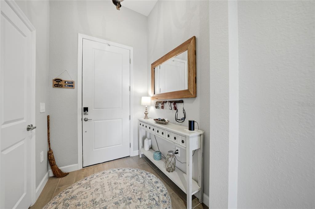 An entryway features a white console table, a wall mirror, and a round patterned rug — 8268 SHORE LAKE DRIVE, ENGLEWOOD, FL
