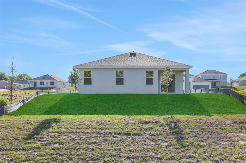 The rear exterior view of a single-story house features a grassy yard and patio — 2920 SUPERMARINE ROAD, TAVARES, FL
