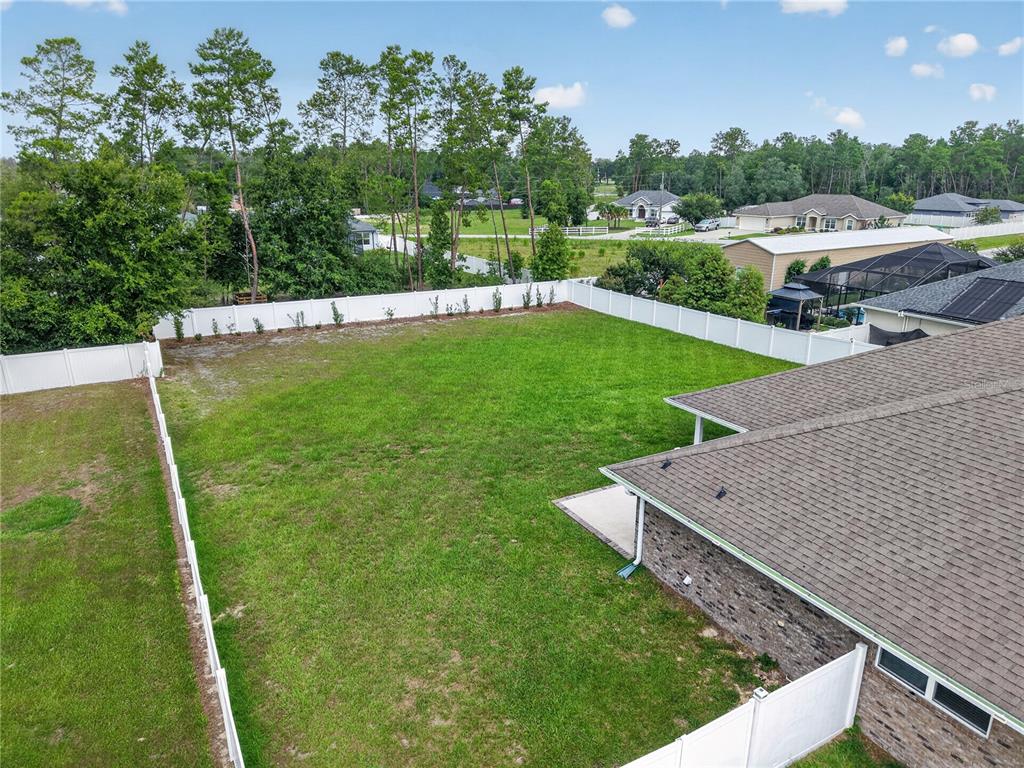 An aerial view shows a fenced backyard with a grassy lawn and a house corner — 9636 SW 40TH TERRACE, OCALA, FL