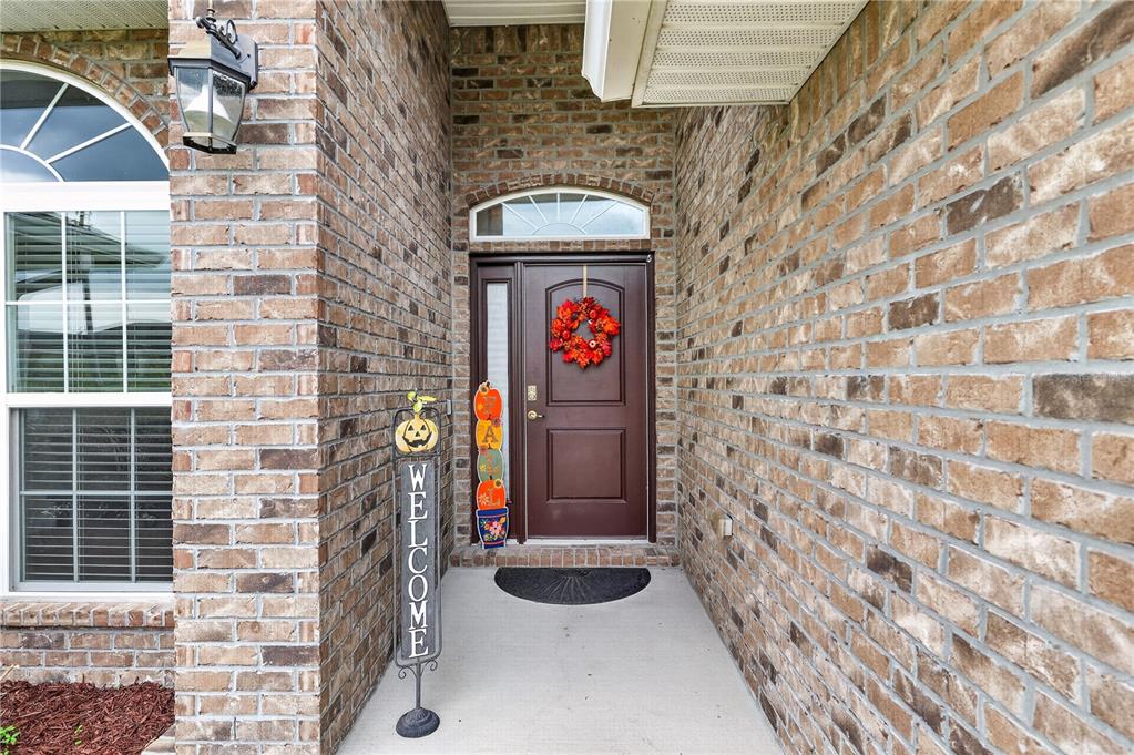 A brick-front home entrance features a brown front door with a wreath and welcome sign — 9636 SW 40TH TERRACE, OCALA, FL