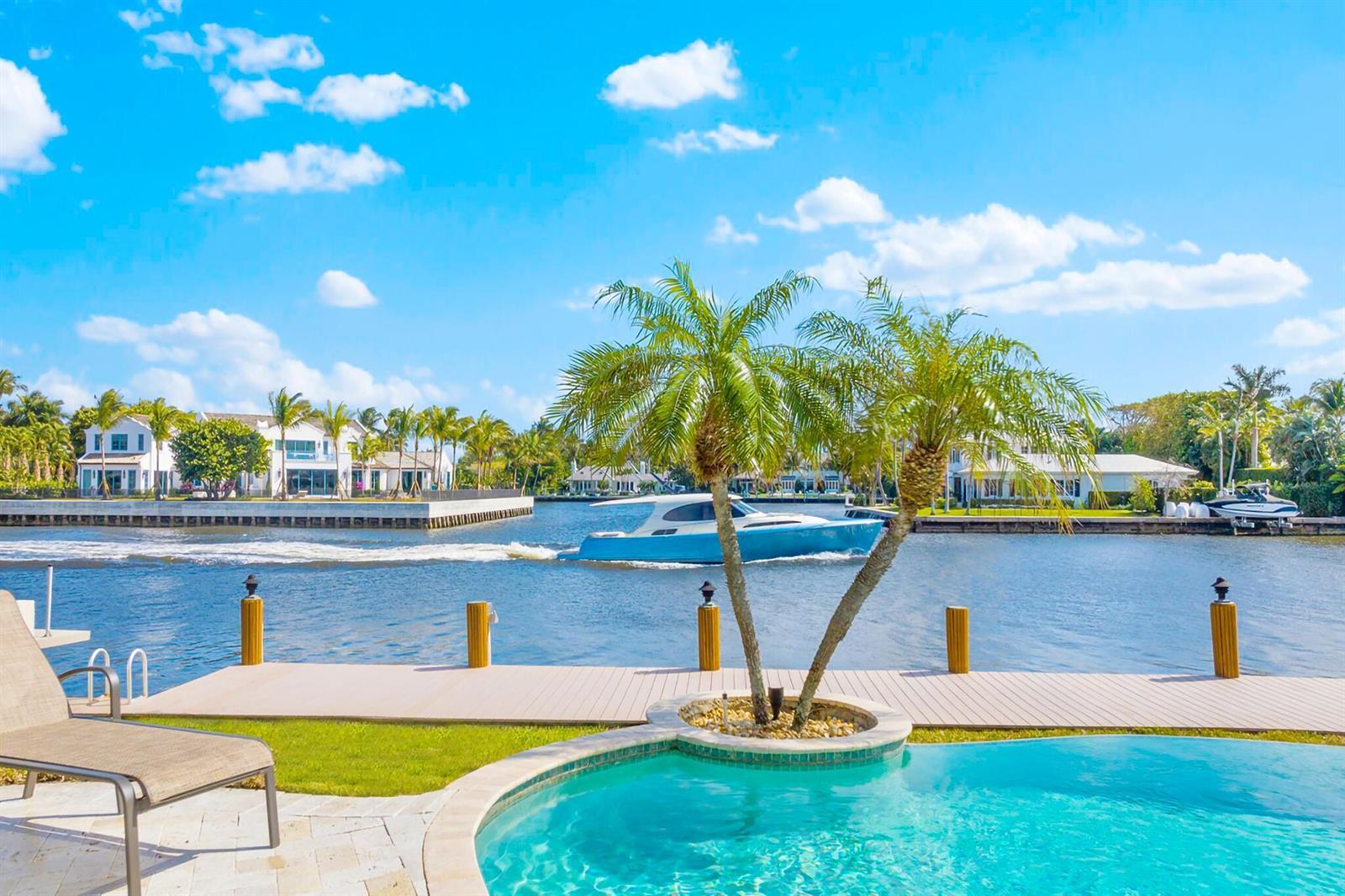 A swimming pool and wooden dock overlook a canal with a boat passing by — 3219 Karen Drive, Delray Beach FL 33483, DELRAY BEACH, FL