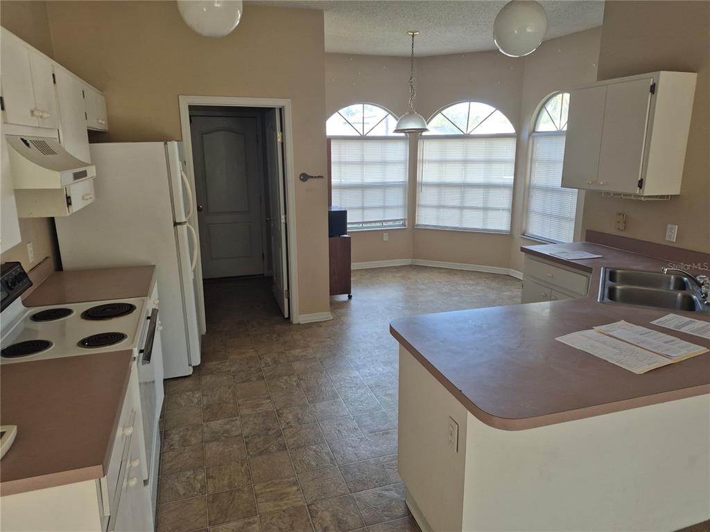 A kitchen with white cabinets, laminate countertops, and a breakfast nook with arched windows — 23300 DOVER DRIVE, LAND O LAKES, FL