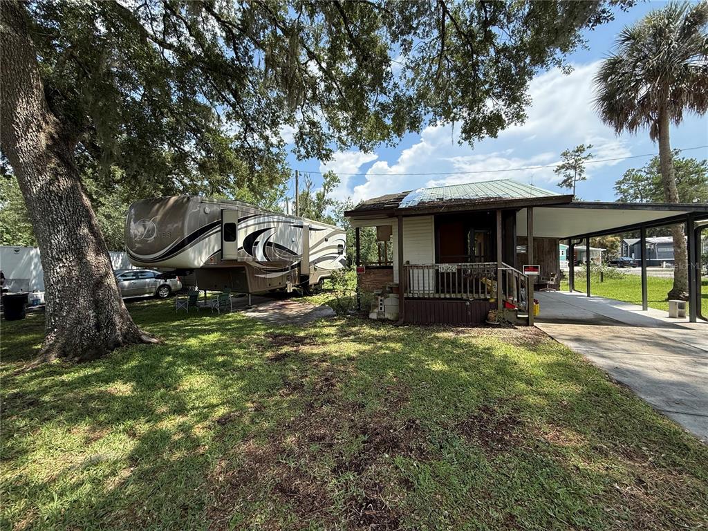 A fifth-wheel RV is parked next to a small house with a covered carport — 2092 CULBREATH ROAD UNIT D24, BROOKSVILLE, FL