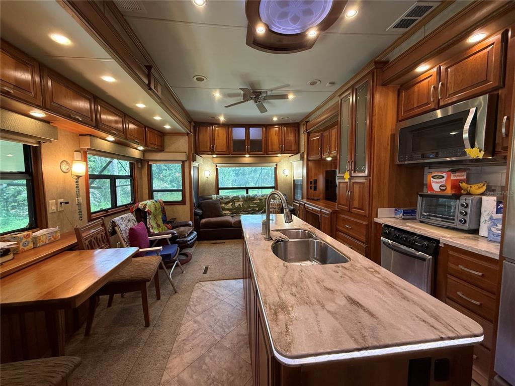 A kitchen and living area in an RV featuring wood cabinetry and a central island — 2092 CULBREATH ROAD UNIT D24, BROOKSVILLE, FL
