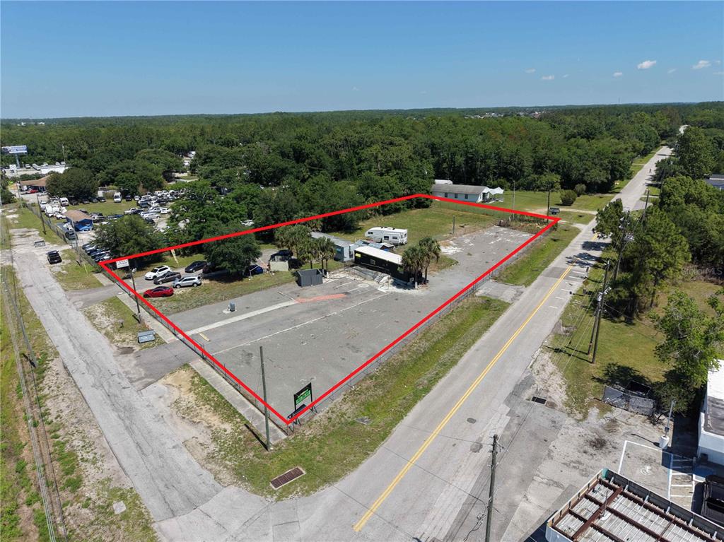 An aerial view shows a fenced, paved commercial lot with a small building and trailer — 17925 OLD CHENEY HWY, ORLANDO, FL