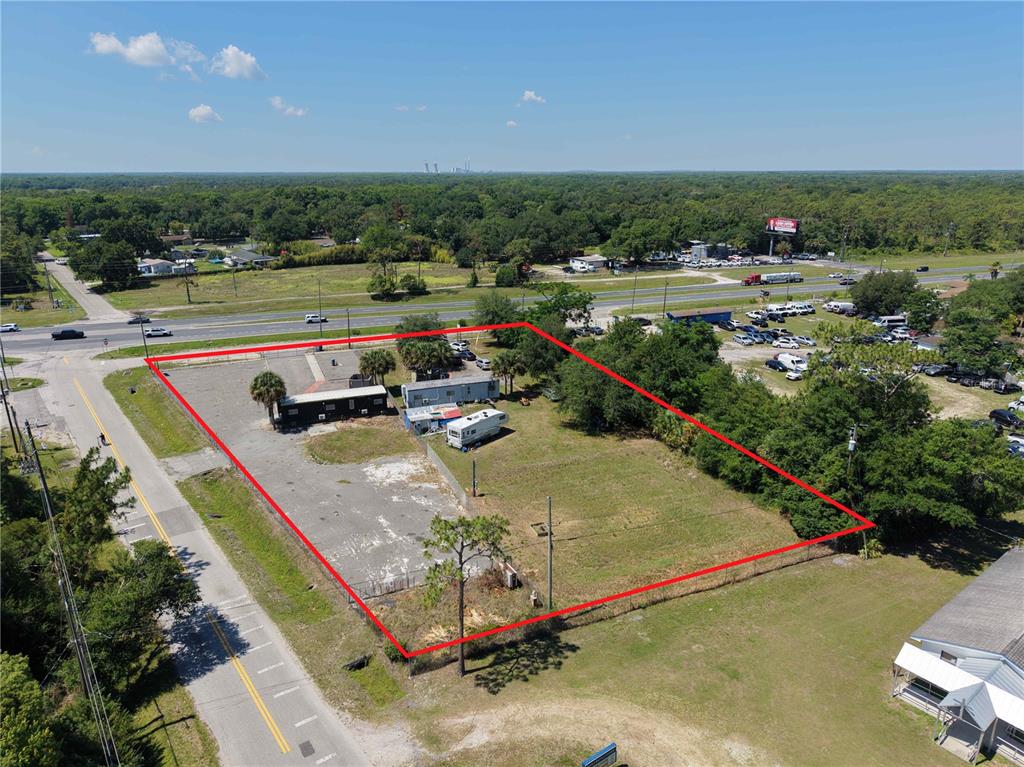 An aerial view shows a fenced, rectangular lot containing two small structures and a trailer — 17925 OLD CHENEY HWY, ORLANDO, FL