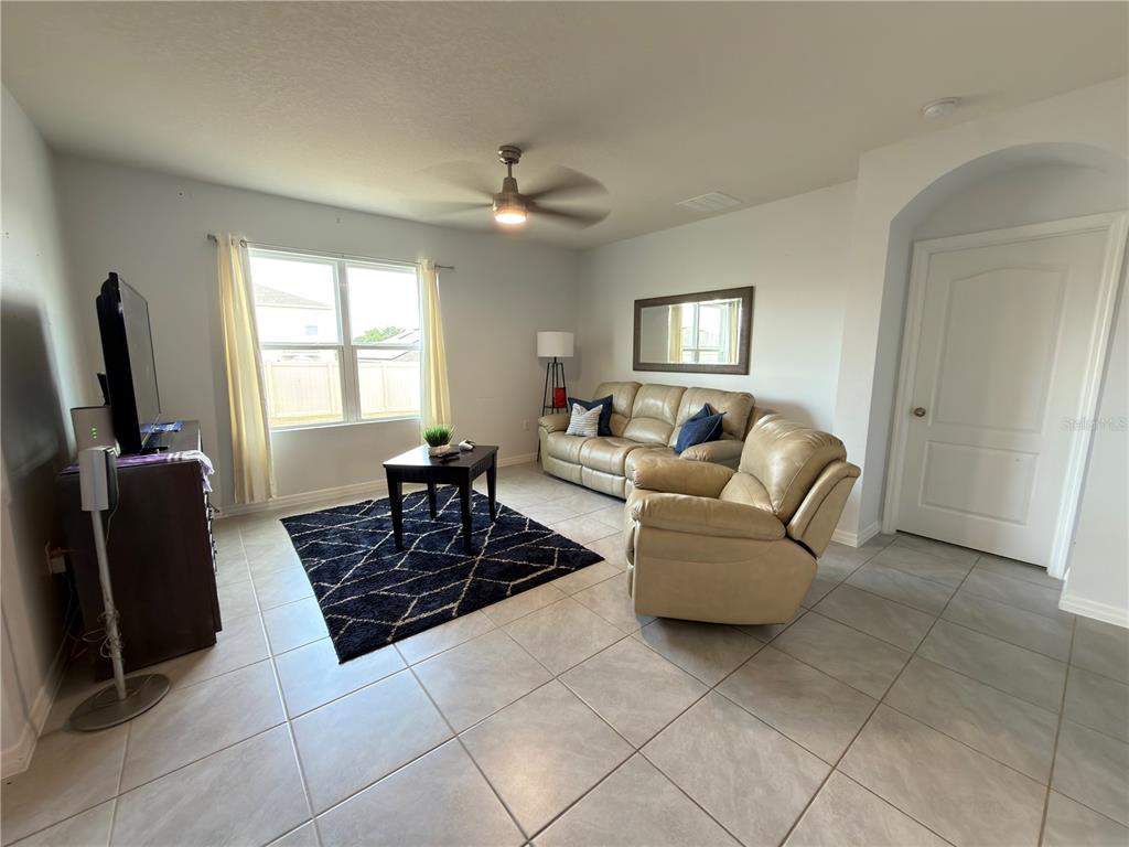 A living room features light tile floors, a tan leather sofa set, and a dark rug — 4079 ALISSA LANE, HAINES CITY, FL