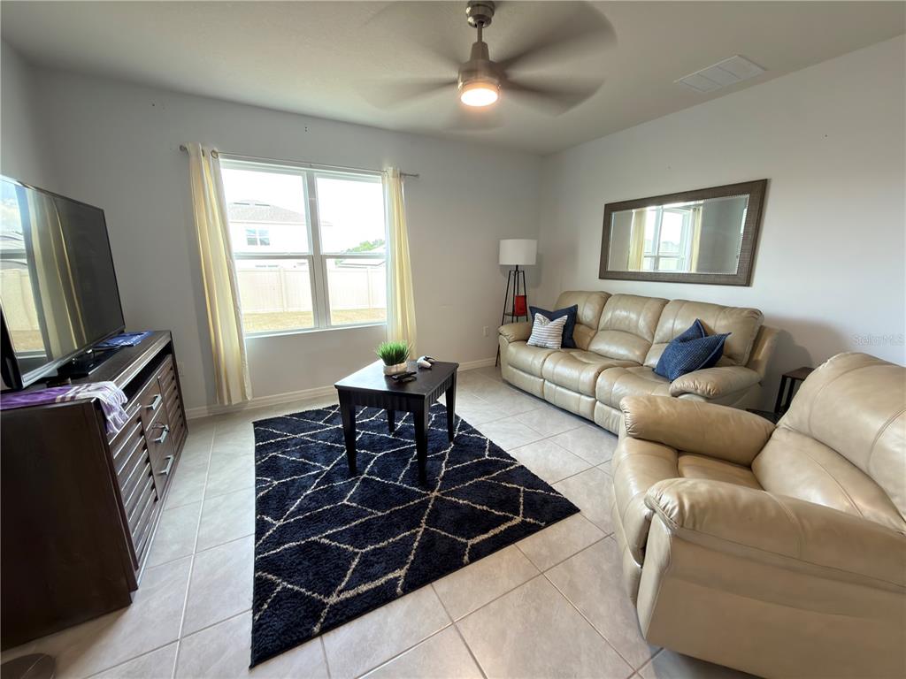 A living room features beige leather furniture, a dark geometric rug, and a ceiling fan — 4079 ALISSA LANE, HAINES CITY, FL