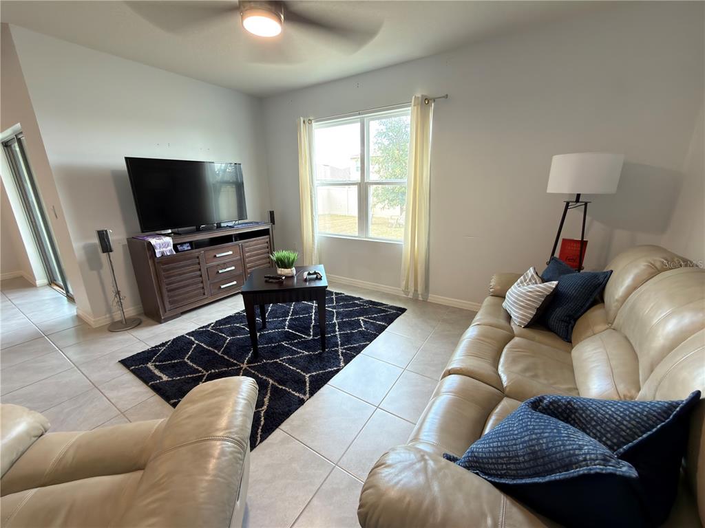 A living room features tile flooring, a dark area rug, a television console, and leather sofas — 4079 ALISSA LANE, HAINES CITY, FL