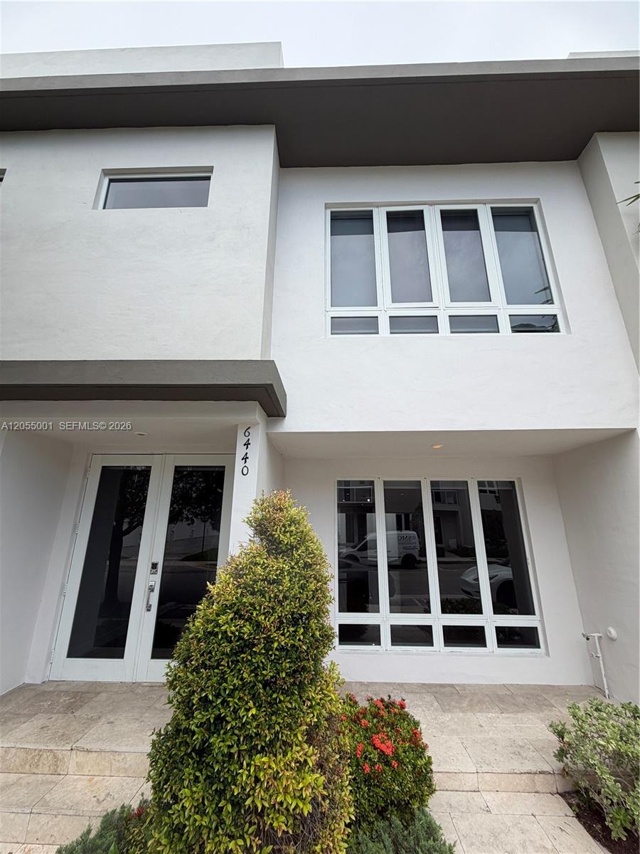 The exterior of a modern two-story white building features large windows and a double-door entrance — 6440 NW 103rd Psge # 6440, Doral FL 33178, DORAL, FL