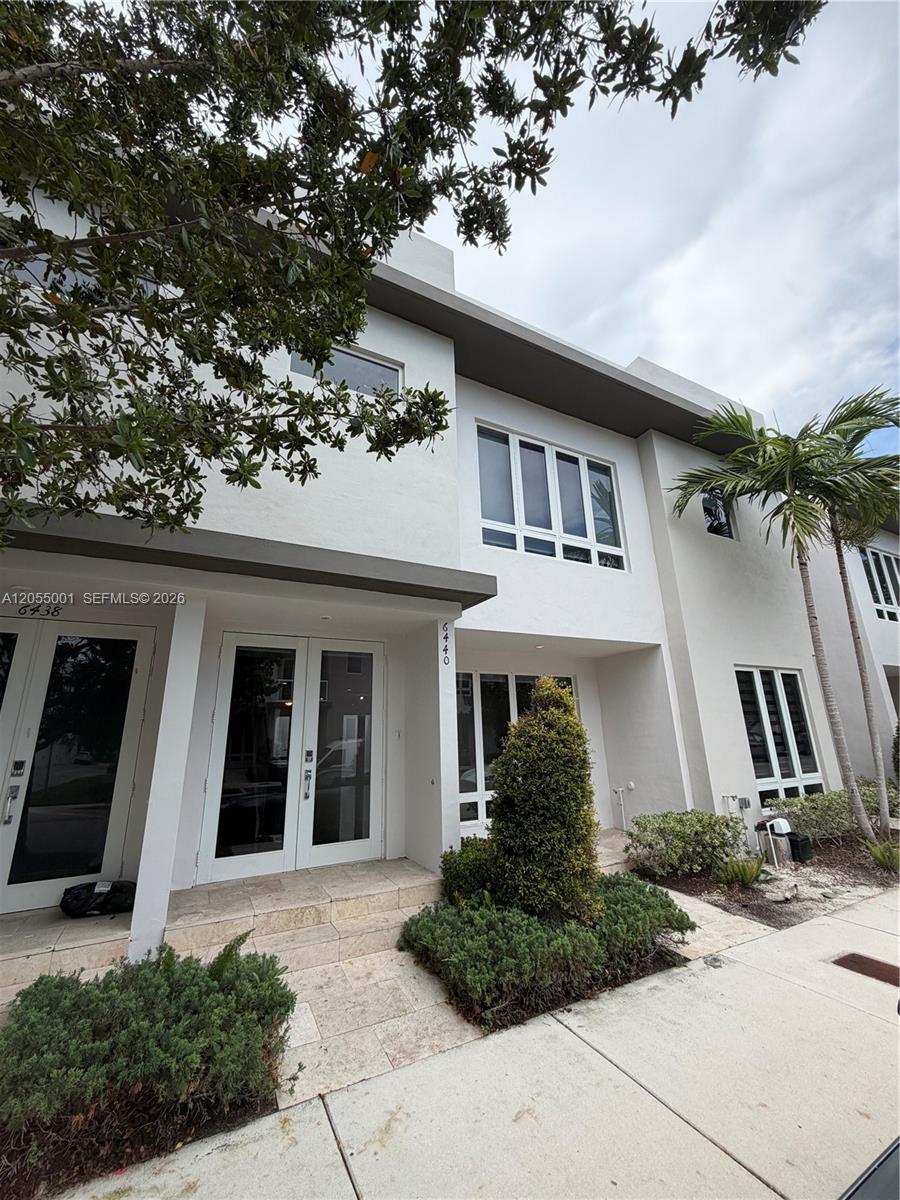 The exterior of a modern two-story white townhouse features large windows and double glass doors — 6440 NW 103rd Psge # 6440, Doral FL 33178, DORAL, FL