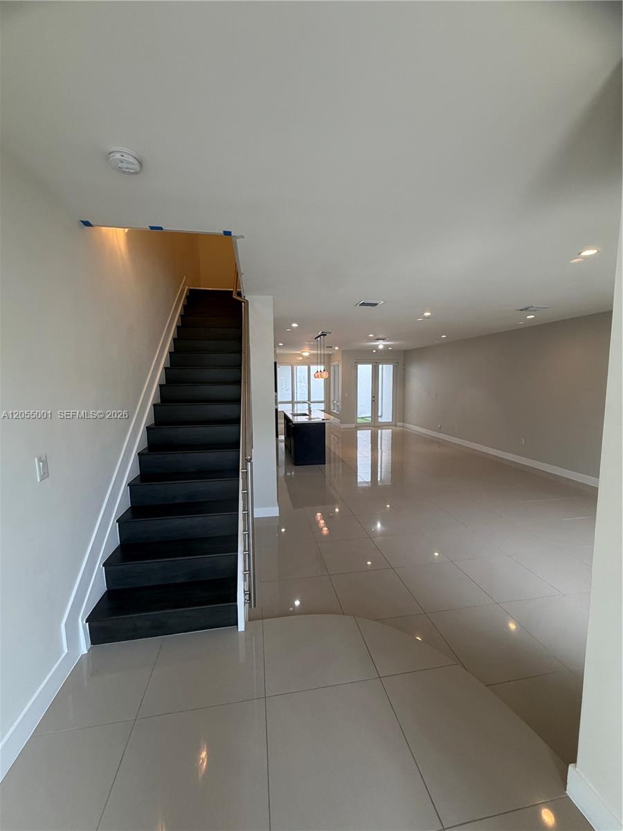 A modern interior features a dark staircase, light tile flooring, and an open-concept kitchen area — 6440 NW 103rd Psge # 6440, Doral FL 33178, DORAL, FL