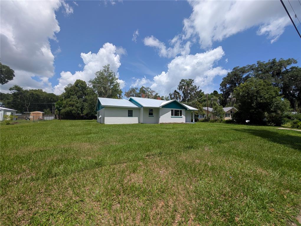 A white, single-story house with a metal roof sits on a large, grassy lot — 414 S PROSPECT STREET, CRESCENT CITY, FL