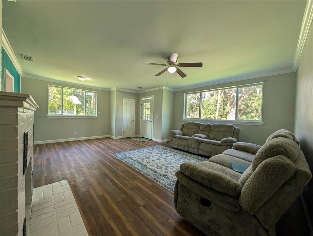 A living room features wood-look flooring, a white brick fireplace, and two gray sofas — 414 S PROSPECT STREET, CRESCENT CITY, FL