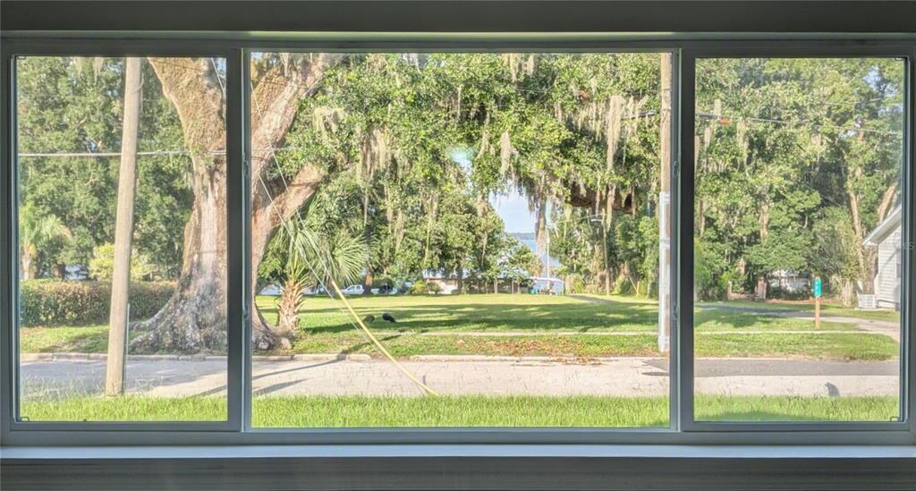 A view of a grassy yard, trees, and a distant lake through a large window — 414 S PROSPECT STREET, CRESCENT CITY, FL