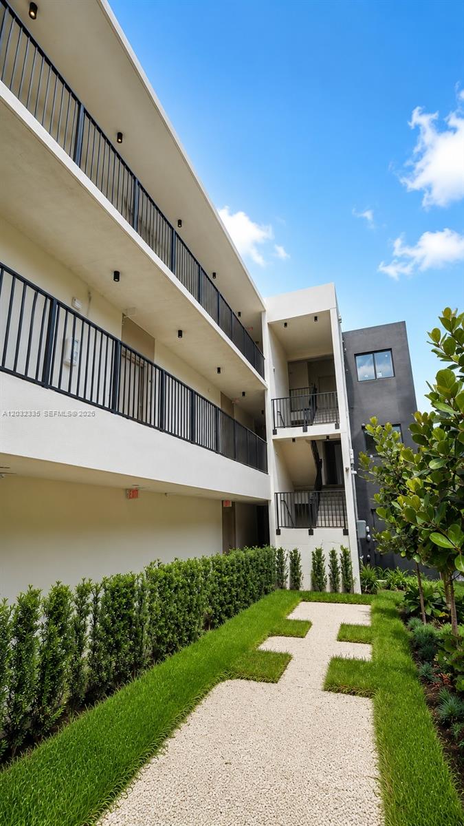 An exterior view of a multi-story apartment building with balconies and a gravel walkway — 8106 NE 1st Ave # 3, Miami FL 33138, MIAMI, FL