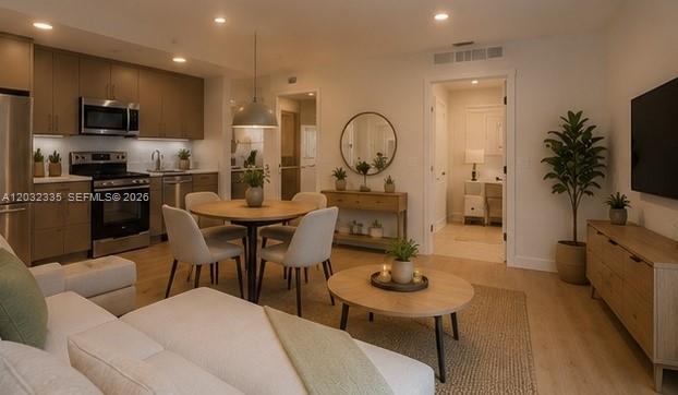 An open-concept living and dining area features a modern kitchen, light wood floors, and neutral furniture — 8106 NE 1st Ave # 3, Miami FL 33138, MIAMI, FL