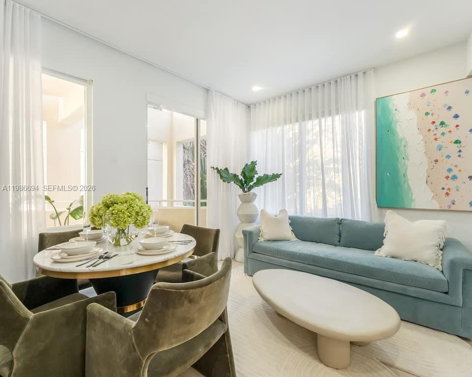 A dining area and living room feature a marble table, blue sofa, and large artwork — 100 Collins Ave # 202, Miami Beach FL 33139, MIAMI BEACH, FL