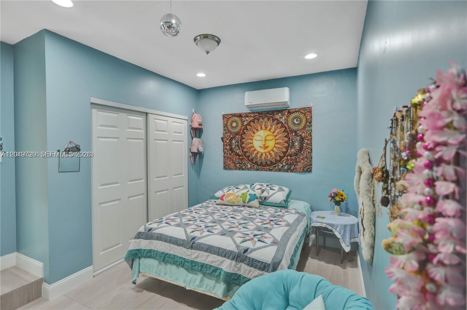 A bedroom with blue walls, a bed, a sun tapestry, and a white closet — 15184 SW 110th St, Miami FL 33196, MIAMI, FL