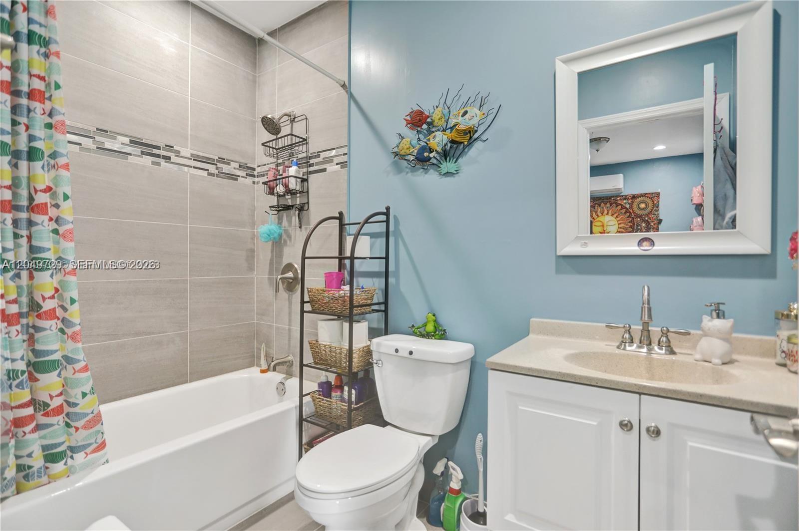 A bathroom features a tiled shower-tub combo, a white toilet, and a blue vanity wall — 15184 SW 110th St, Miami FL 33196, MIAMI, FL