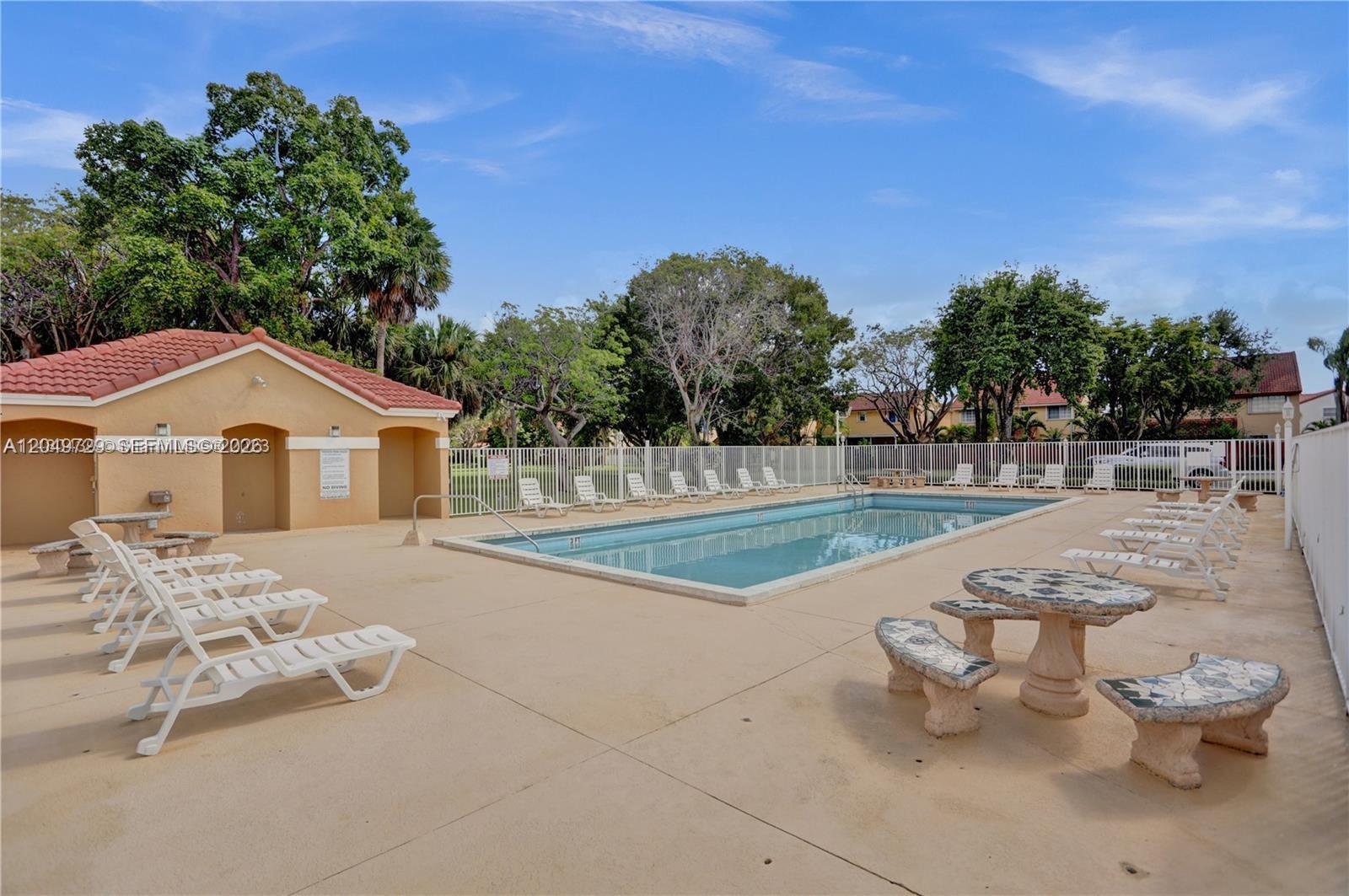 An outdoor swimming pool area features lounge chairs, a stone table, and a small building — 15184 SW 110th St, Miami FL 33196, MIAMI, FL