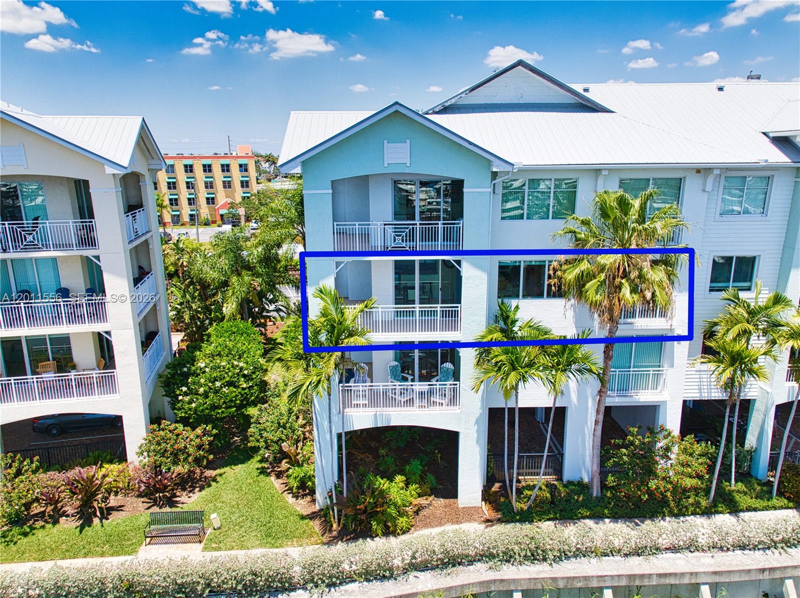 An exterior view of a multi-story building featuring balconies and surrounding palm trees — 815 NW Flagler Ave # 305, Stuart FL 34994, STUART, FL
