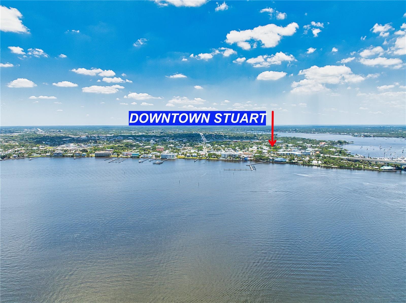 This aerial view shows a waterfront city skyline with a red arrow pointing toward downtown — 815 NW Flagler Ave # 305, Stuart FL 34994, STUART, FL