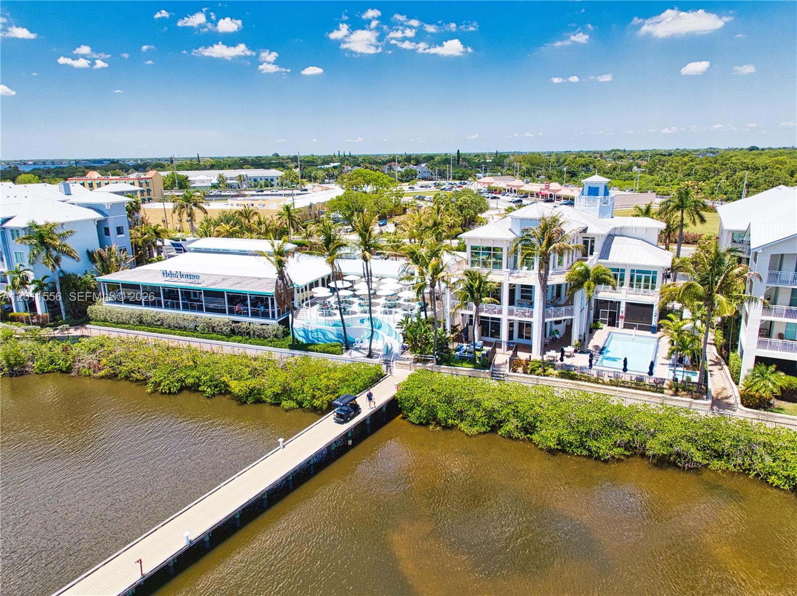 An aerial view shows a waterfront restaurant and adjacent building with a pool and pier — 815 NW Flagler Ave # 305, Stuart FL 34994, STUART, FL