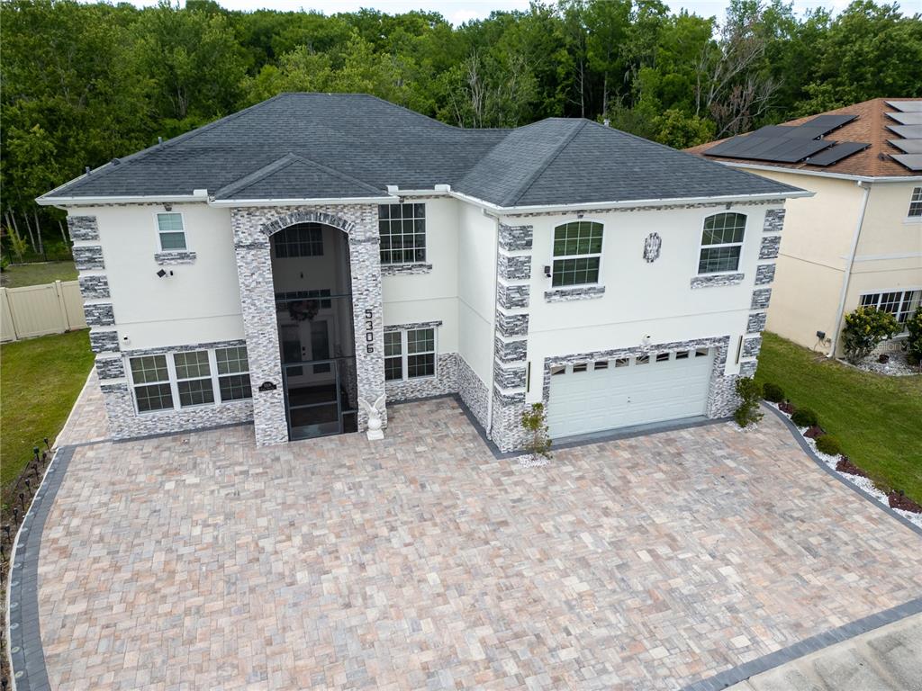 An aerial view of a two-story house with a stone facade and paved driveway — 5306 CORAL VINE LANE, KISSIMMEE, FL
