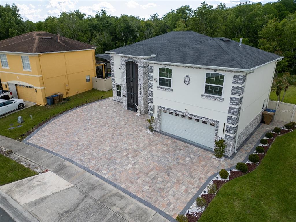 An aerial view shows a two-story house with a stone facade and a paved driveway — 5306 CORAL VINE LANE, KISSIMMEE, FL