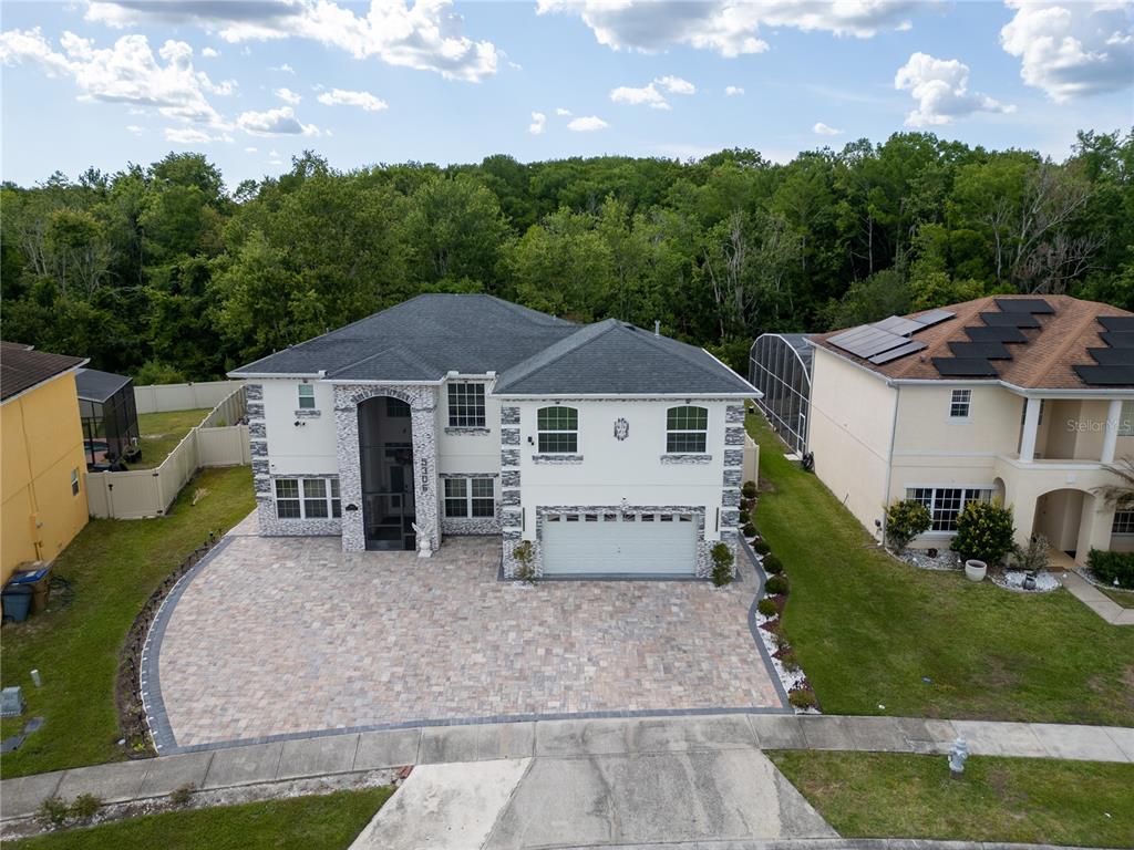An aerial view of a two-story house with a paved driveway and a wooded backyard — 5306 CORAL VINE LANE, KISSIMMEE, FL