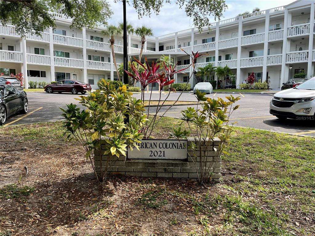 A brick sign for American Colonial 2021 sits in front of a multi-story apartment building — 2021 AUSTRALIA WAY W UNIT 59, CLEARWATER, FL