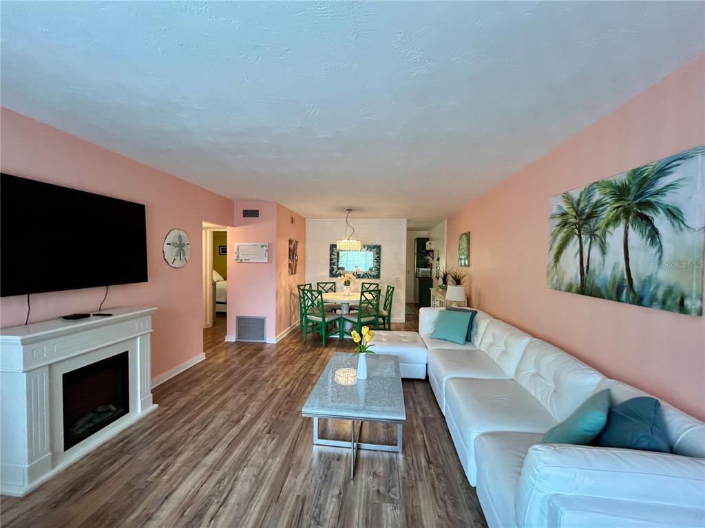 A living room with a white fireplace, sectional sofa, and dining area with green chairs — 2021 AUSTRALIA WAY W UNIT 59, CLEARWATER, FL
