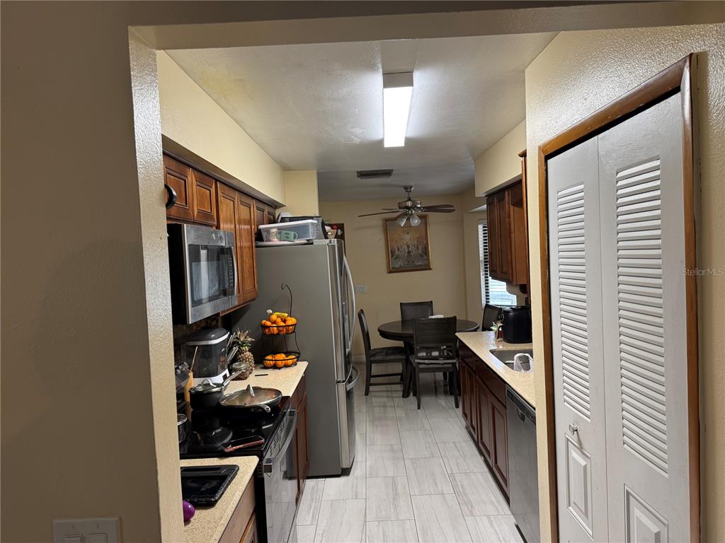 A galley kitchen features wood cabinets, stainless steel appliances, and an adjacent dining area — 1410 MONITOR AVENUE, ORLANDO, FL