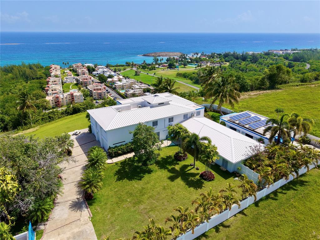 An aerial view shows a white house with a metal roof and solar panels — 665 AQUAMARINA, ISABELA, PR