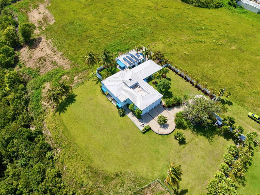 An aerial view of a white house with a metal roof surrounded by green fields — 665 AQUAMARINA, ISABELA, PR
