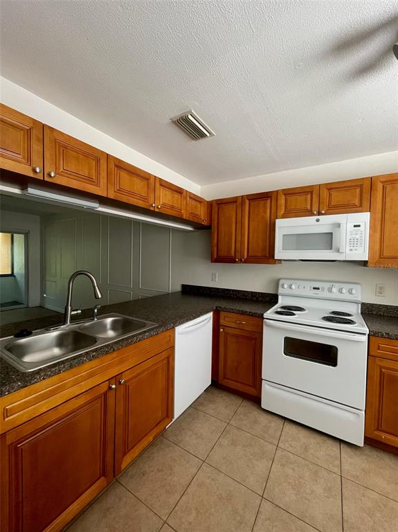 A kitchen features wood cabinets, dark countertops, a white stove, and a double-basin sink — 950 BELTREES STREET, DUNEDIN, FL
