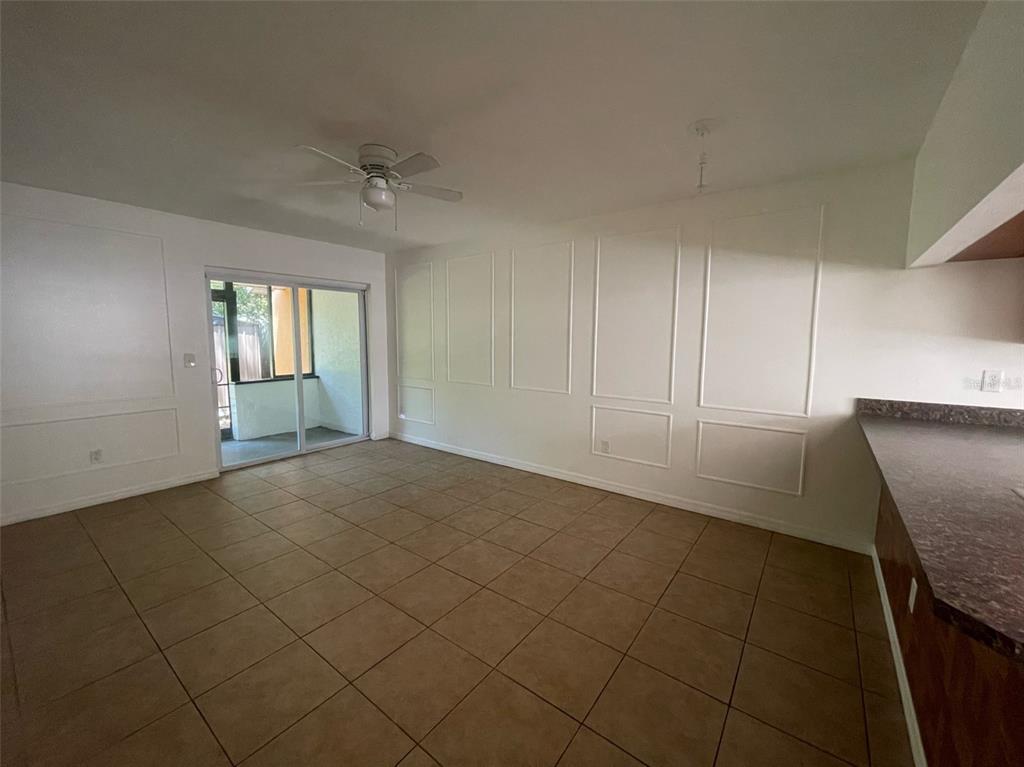 An empty room with tiled floors, wall molding, a ceiling fan, and a sliding glass door — 950 BELTREES STREET, DUNEDIN, FL