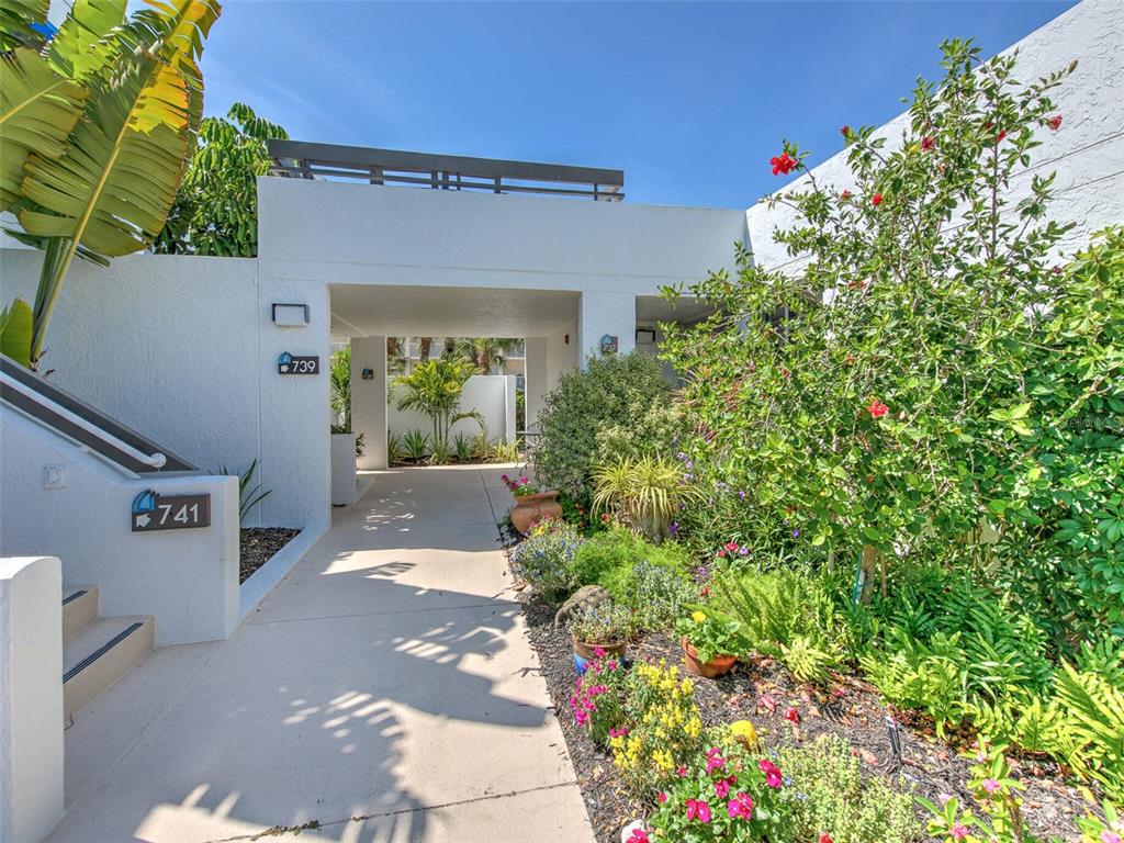 A concrete walkway leads to a covered entryway between two white stucco building units — 739 BAYPORT WAY UNIT 739, LONGBOAT KEY, FL