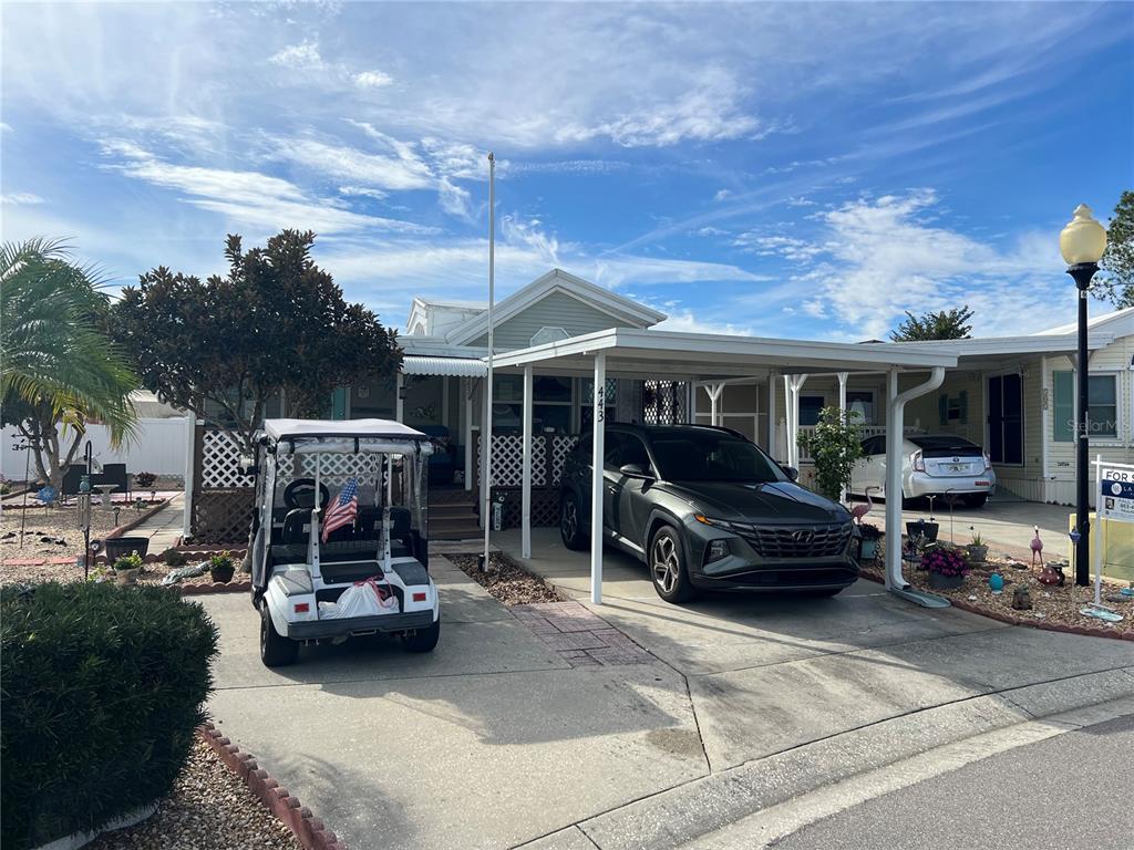 A mobile home features a covered porch with white lattice railings and a turquoise front door — 443 PANSY STREET, DAVENPORT, FL