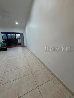 A room with light-colored tile flooring and a large blank wall leads to a sliding door — 108 PINE ISLAND CIRCLE, KISSIMMEE, FL