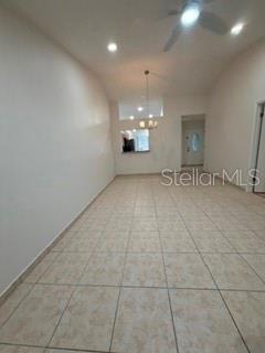 An empty room with light-colored tile flooring, a ceiling fan, and a pass-through window — 108 PINE ISLAND CIRCLE, KISSIMMEE, FL