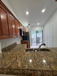 A kitchen features wood cabinets, granite countertops, a double sink, and a sliding glass door — 108 PINE ISLAND CIRCLE, KISSIMMEE, FL