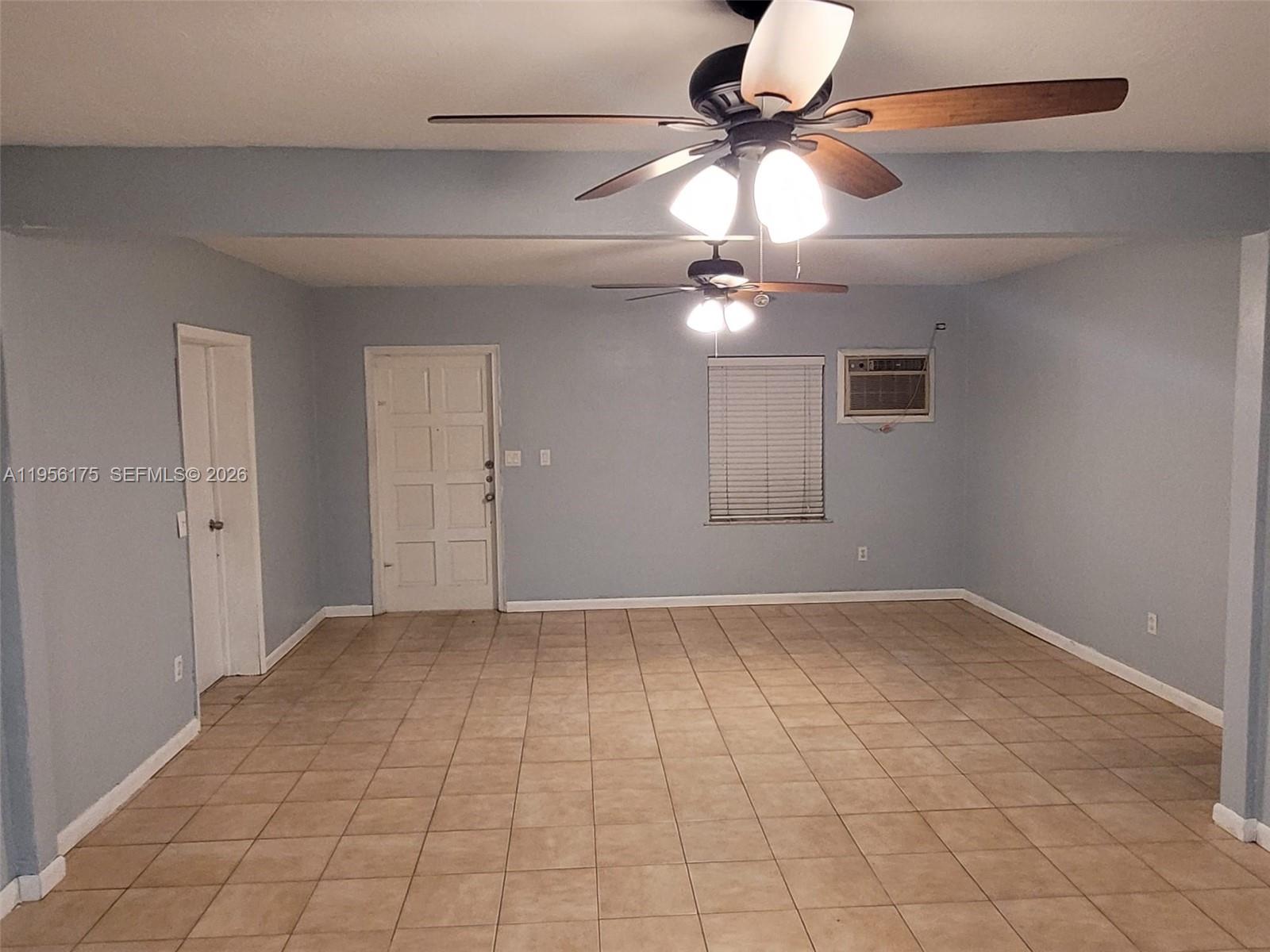 An empty room features light blue walls, tan tile flooring, and two ceiling fans — 2828 SW 3rd St, Miami FL 33135, MIAMI, FL