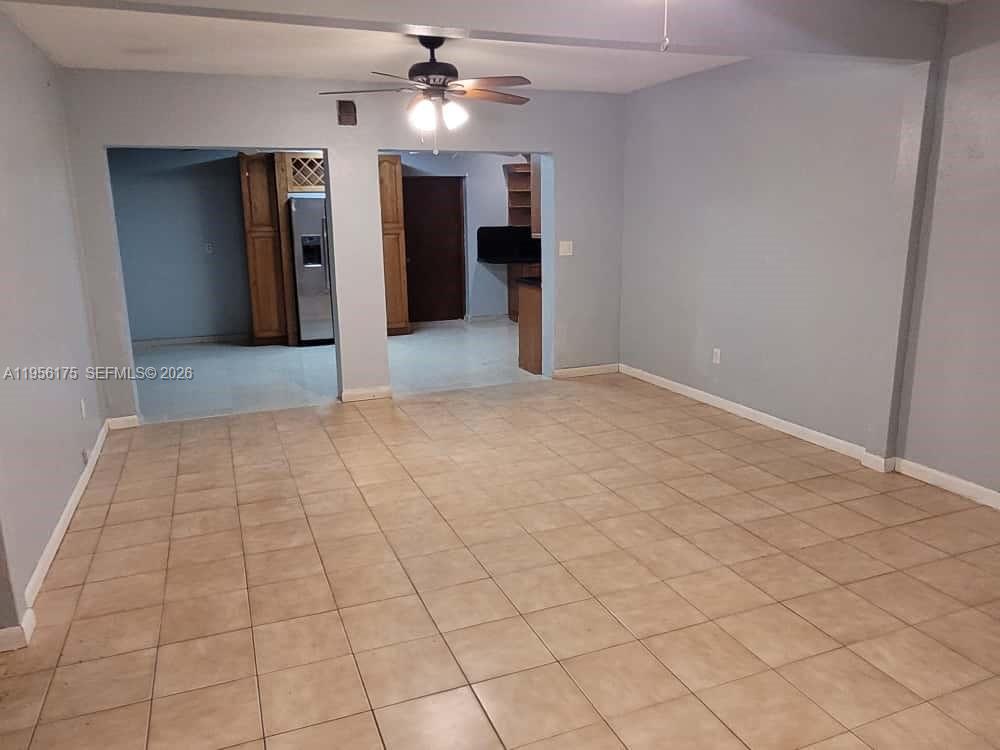A living room with light-colored tile flooring leads into a kitchen with wooden cabinets — 2828 SW 3rd St, Miami FL 33135, MIAMI, FL