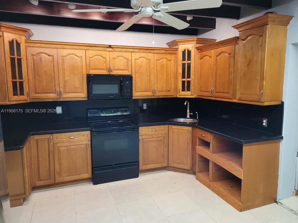 A kitchen features honey-toned wood cabinets, black countertops, and black appliances — 2828 SW 3rd St, Miami FL 33135, MIAMI, FL